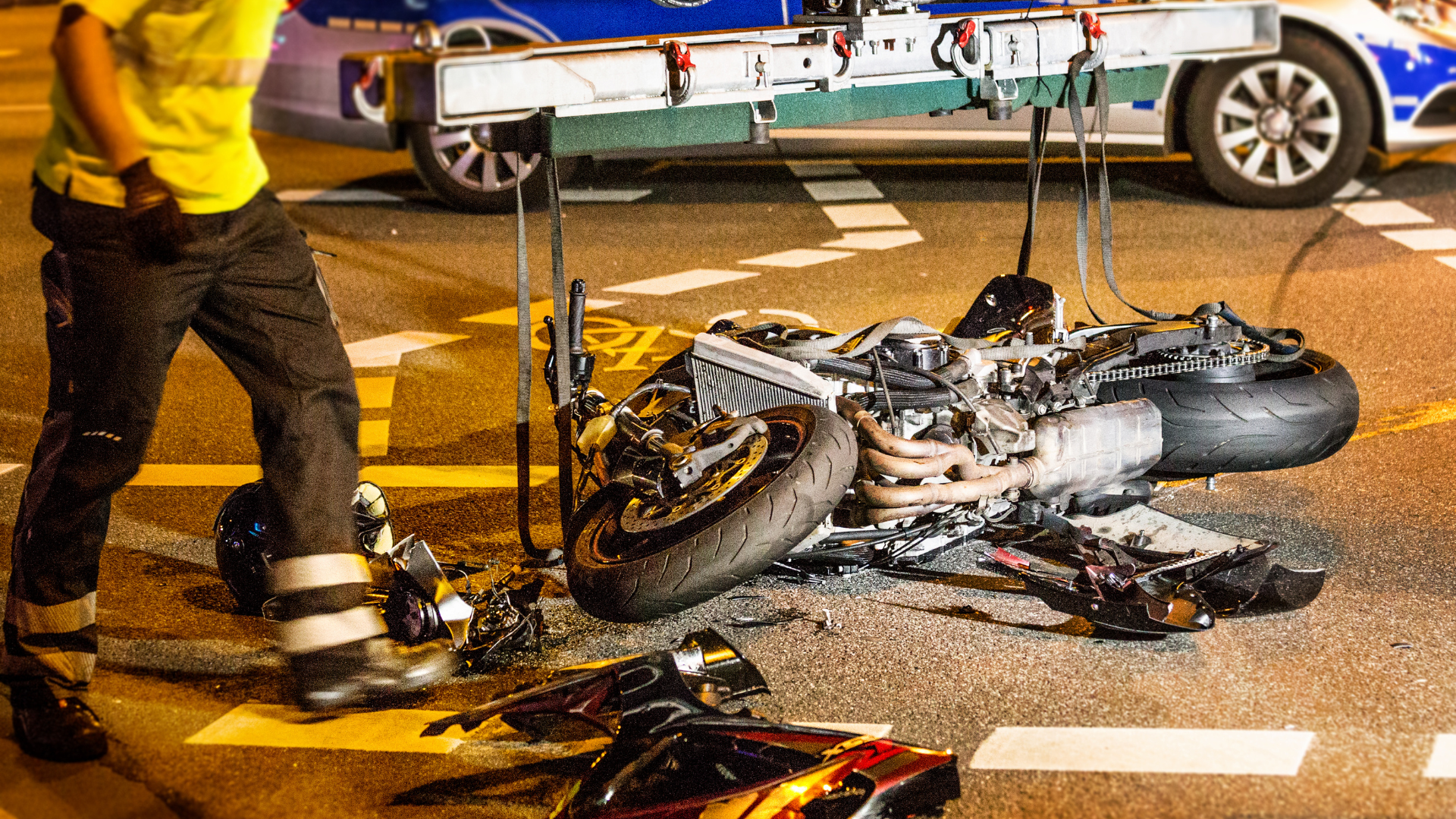 A man is standing next to a motorcycle that has been damaged in a motorcycle accident.