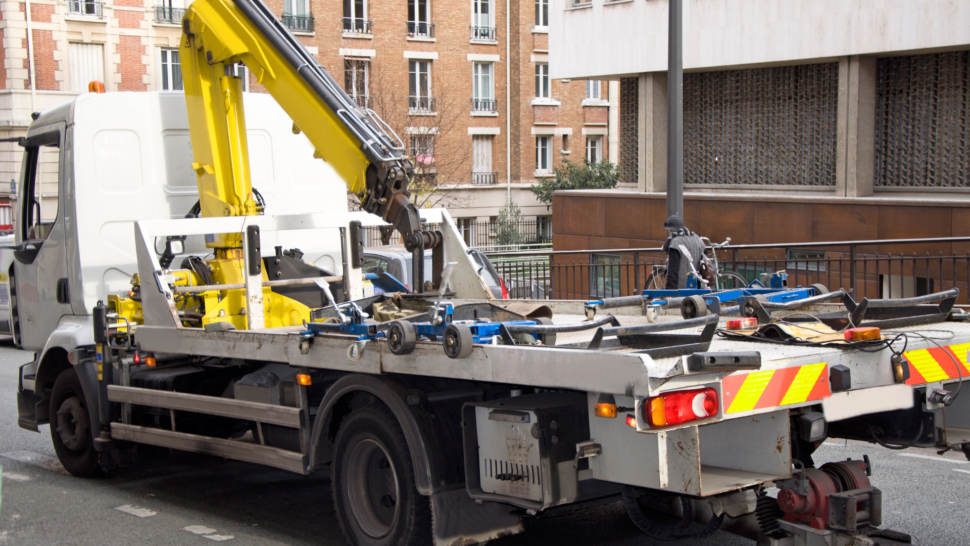 A tow truck with a crane on the back is parked on the side of the road.