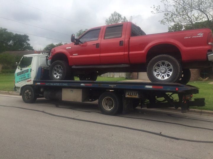 A red truck is sitting on top of a tow truck.