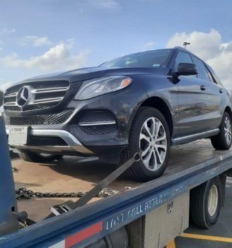 A mercedes benz gle is being towed by a tow truck.