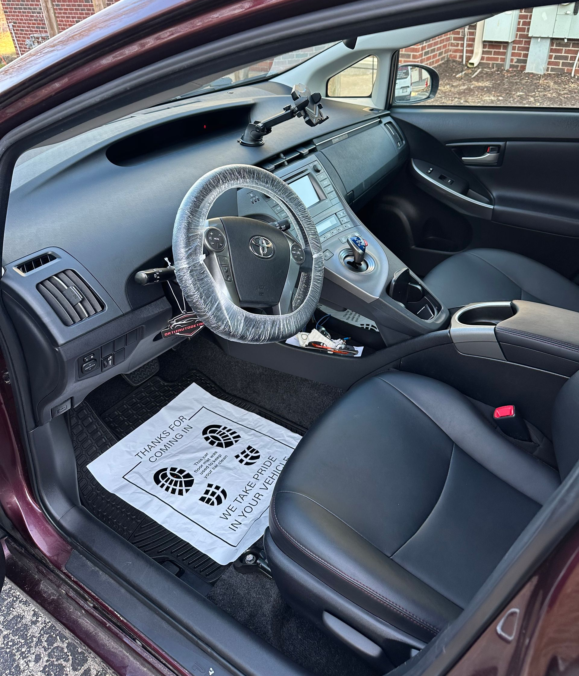 Car interior with custom gray dashboard and steering wheel cover, black seats, and a white floor mat
