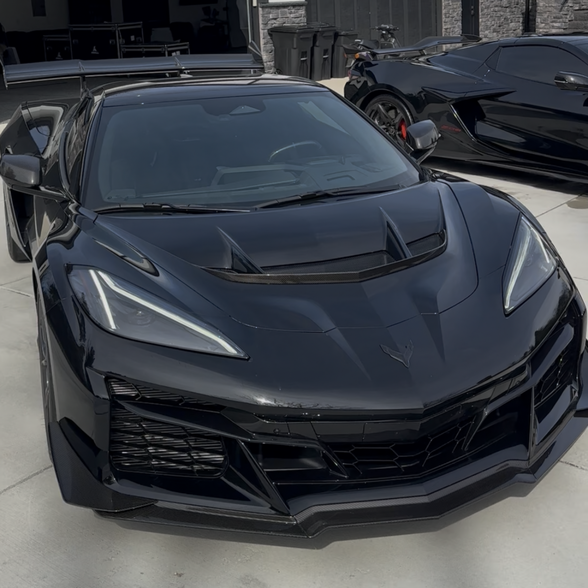 Black sports car parked outdoors, front view with sharp angular headlights and hood vents.