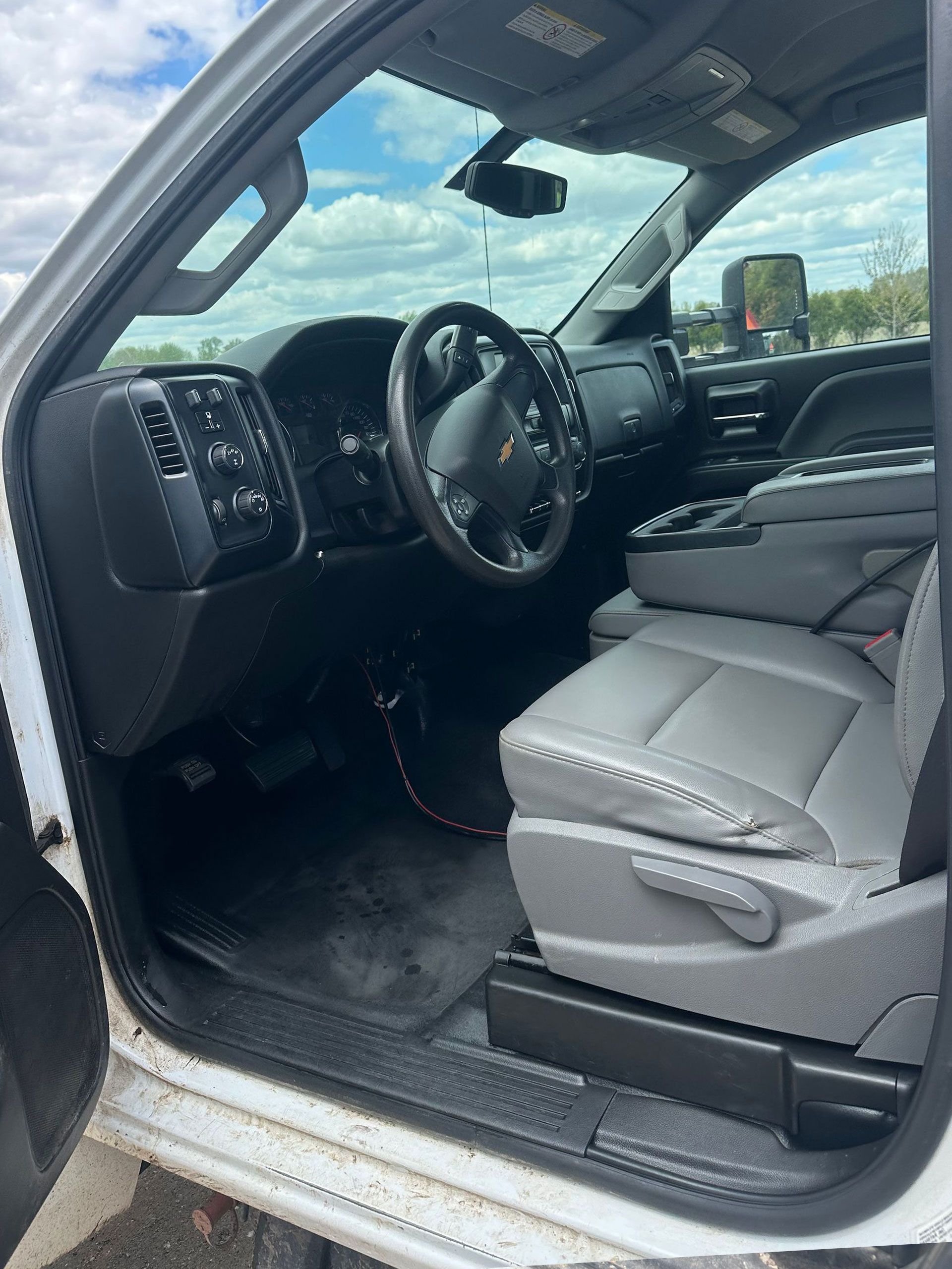 Car interior with gray seats, red door trim, and a steering wheel covered in a patterned wrap.