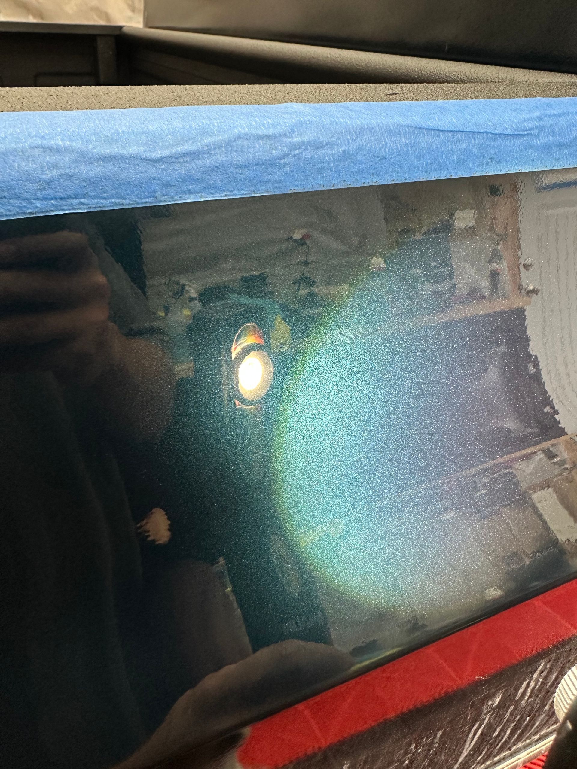 Glowing light reflecting on a dark screen, with blue and red edges visible.