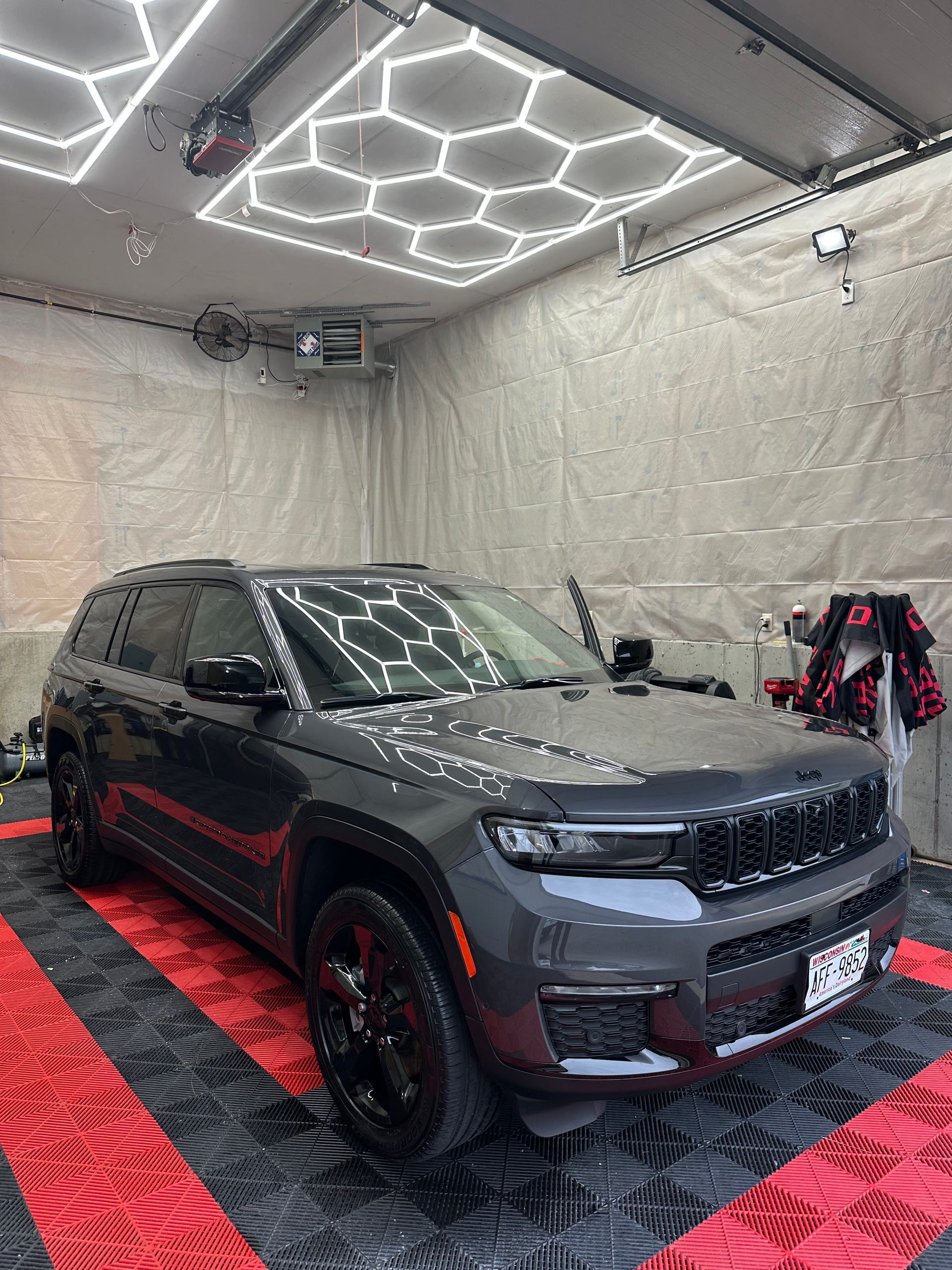 Black pickup truck in a garage with reflective ceiling insulation and red-black checkered floor mats