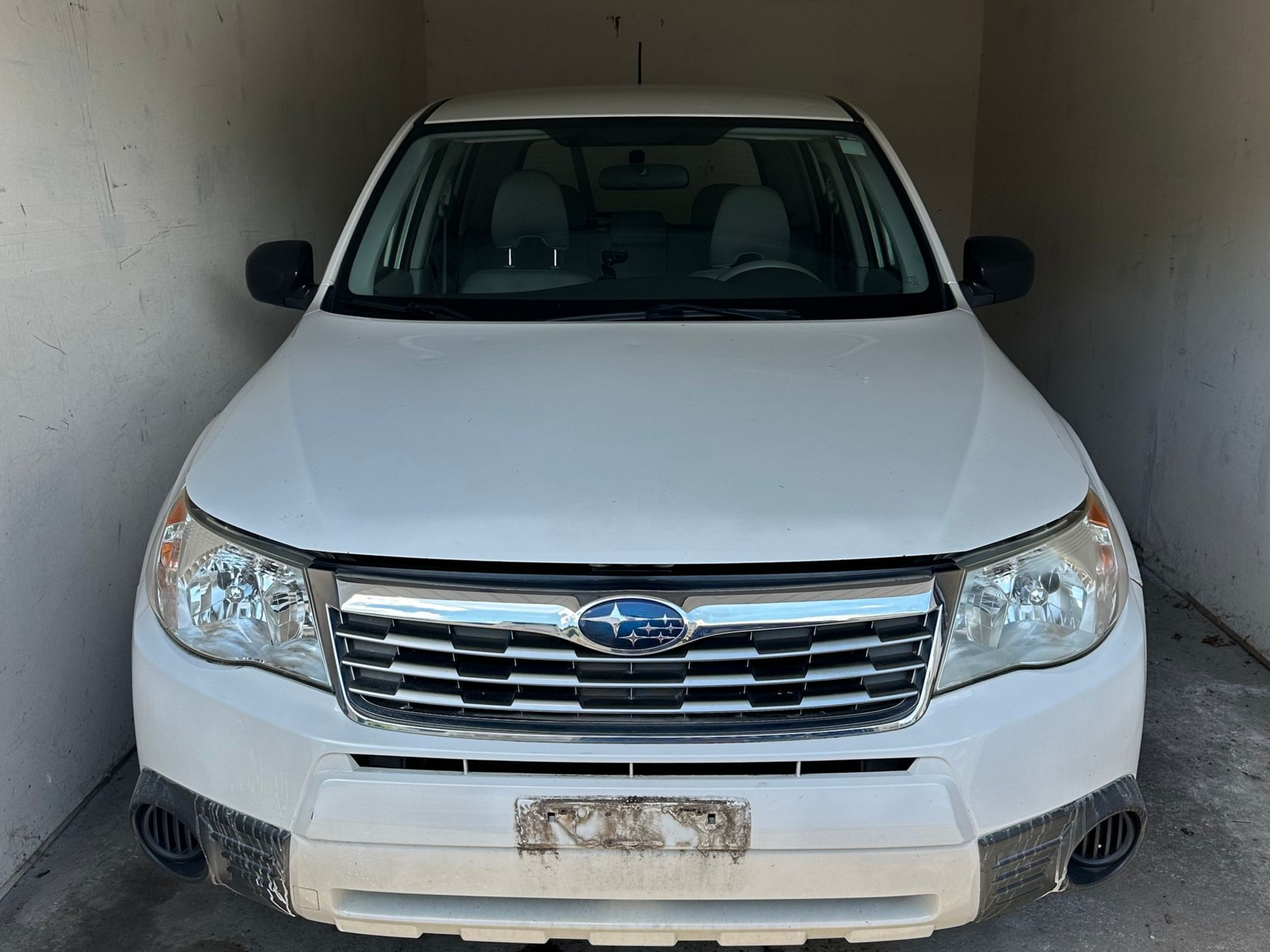 White Subaru SUV parked in a garage, front view