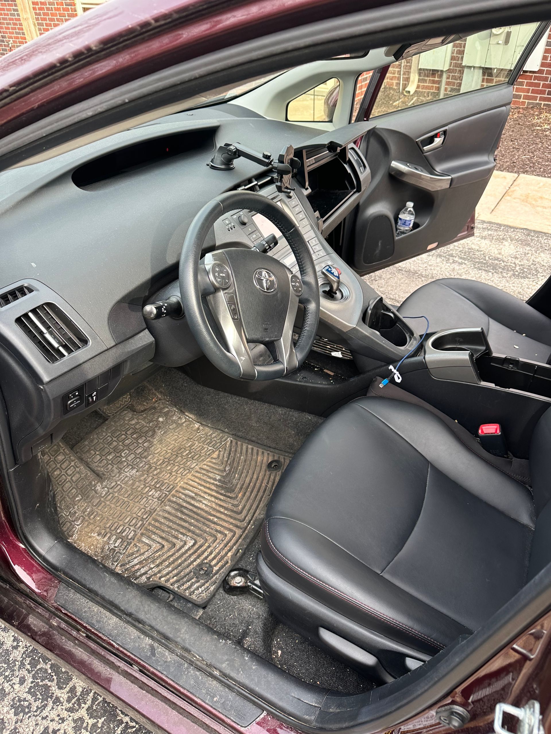 Damaged car interior with deployed airbags and broken windshield, driver’s door open