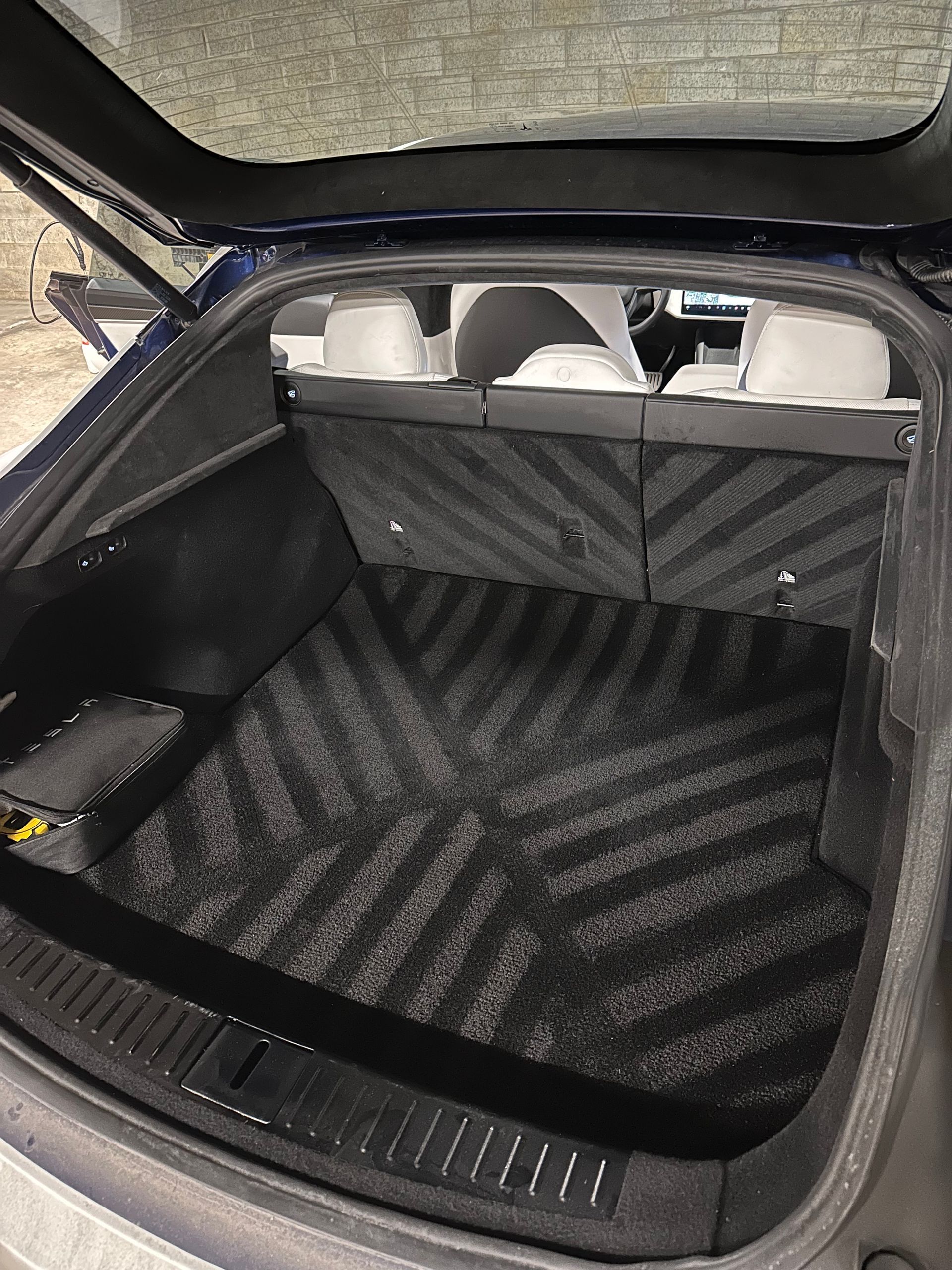 Empty black-lined car trunk with rear seats visible through the open hatch.