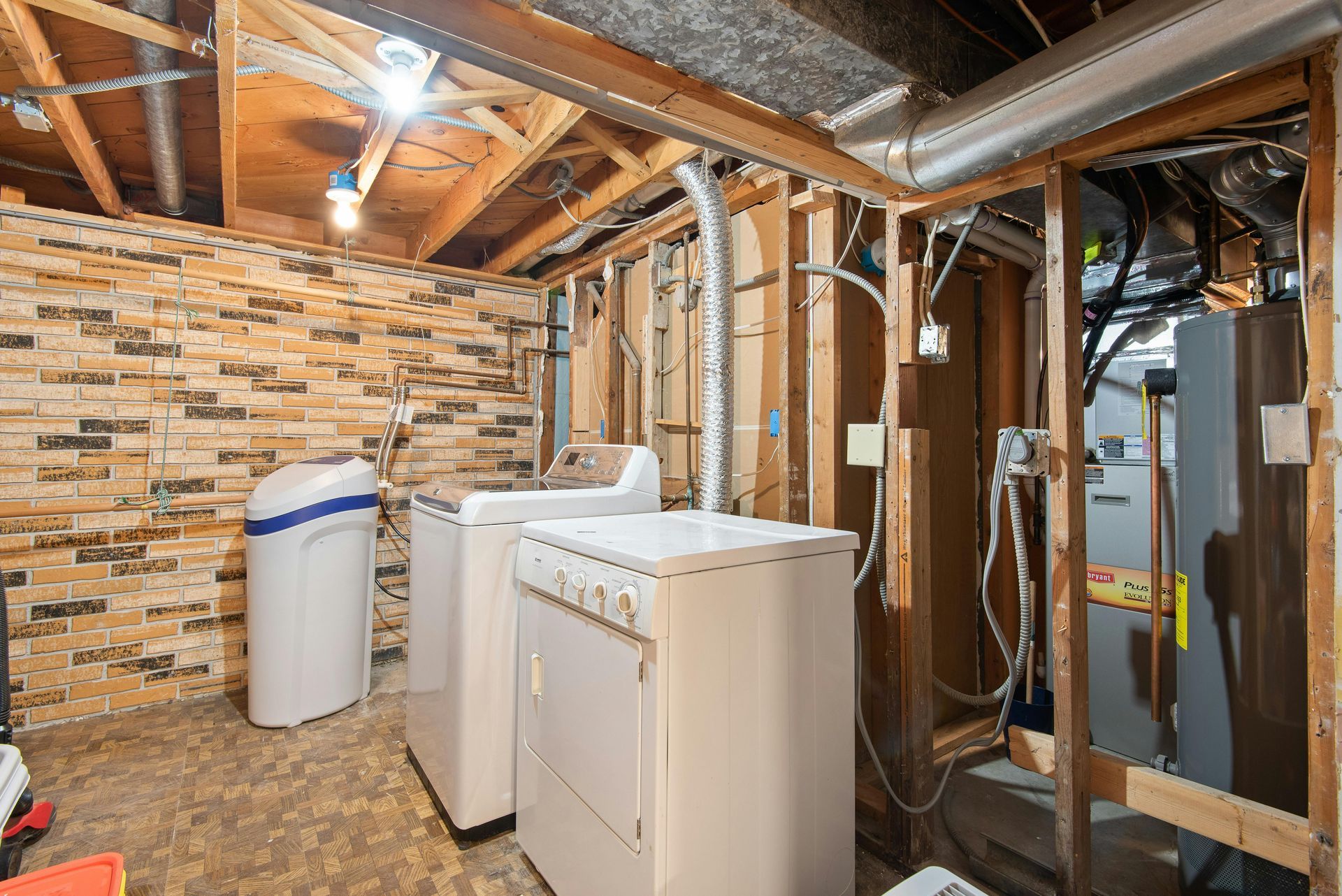 Laundry room with washer, dryer, water heater, and exposed ductwork in a basement.