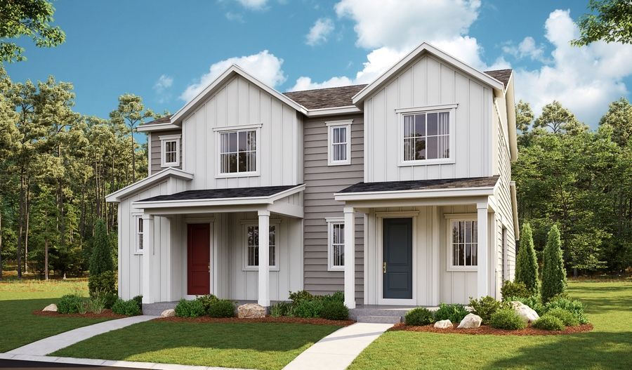A white and gray house with a red door is sitting on top of a lush green lawn.