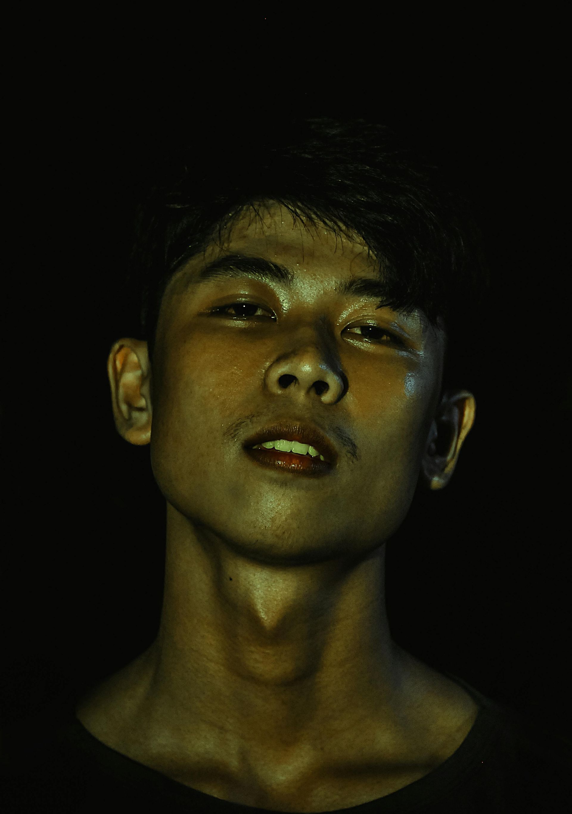 A close up of a young man 's face in the dark.