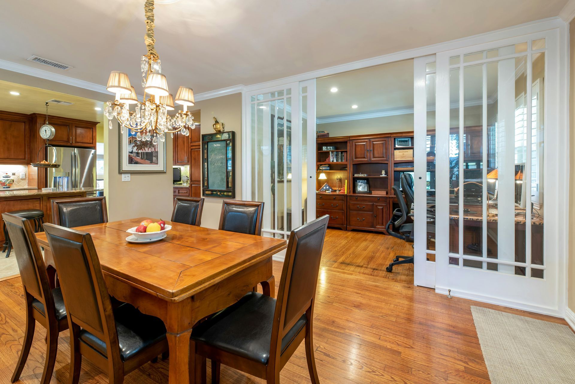 A dining room with a wooden table and chairs and a chandelier.