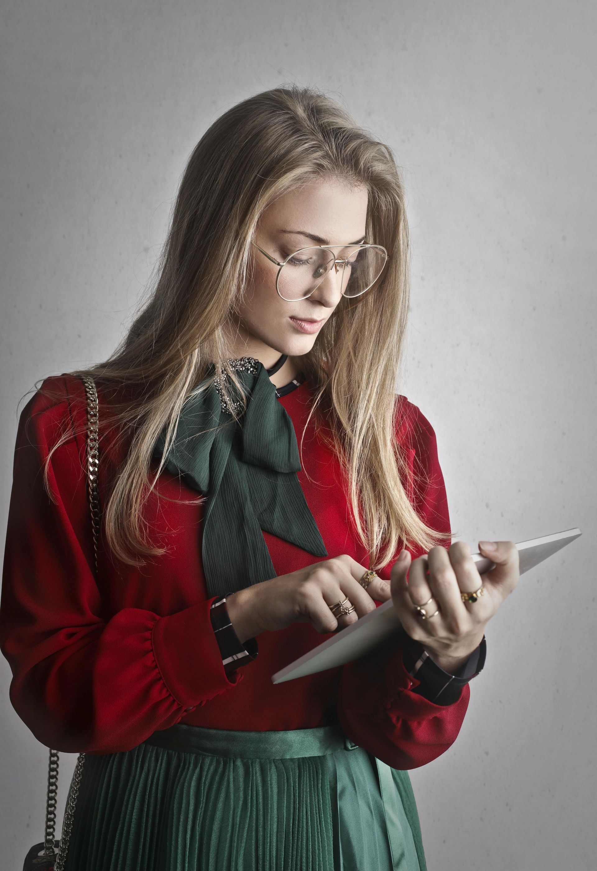 A woman in a red sweater and green skirt is using a tablet computer.