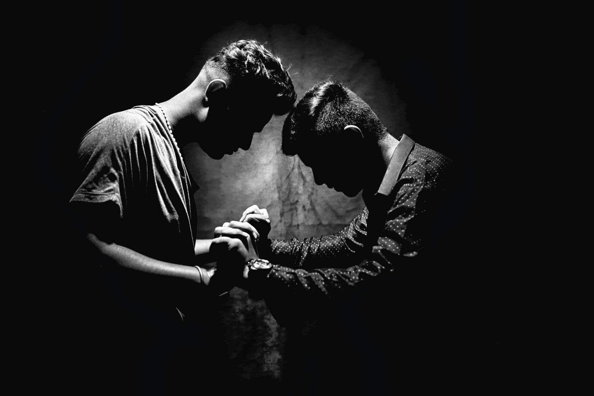 Two men are praying together in a black and white photo.