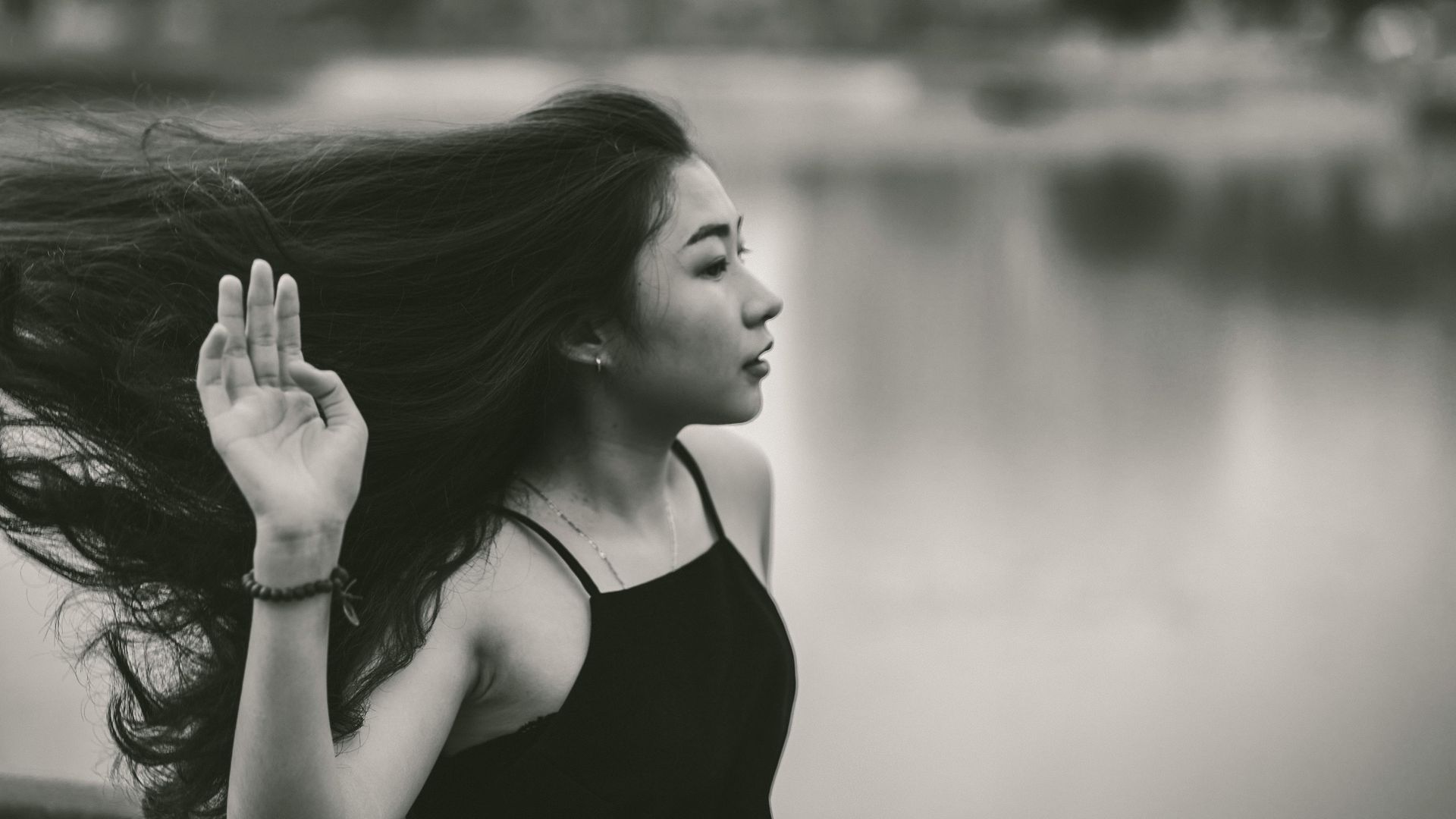 A black and white photo of a woman with long hair blowing in the wind.