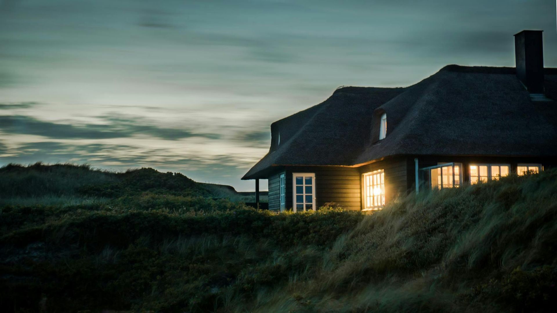 A house is lit up at night in the middle of a field.