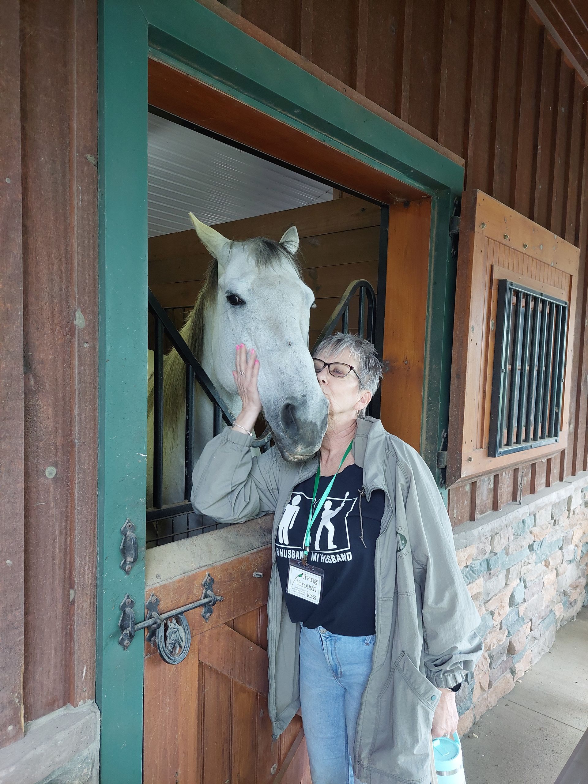 A woman standing next to a horse wearing a t-shirt with the letter k on it