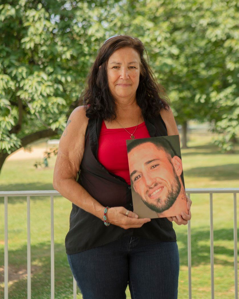 A woman is holding a picture of a man 's face.