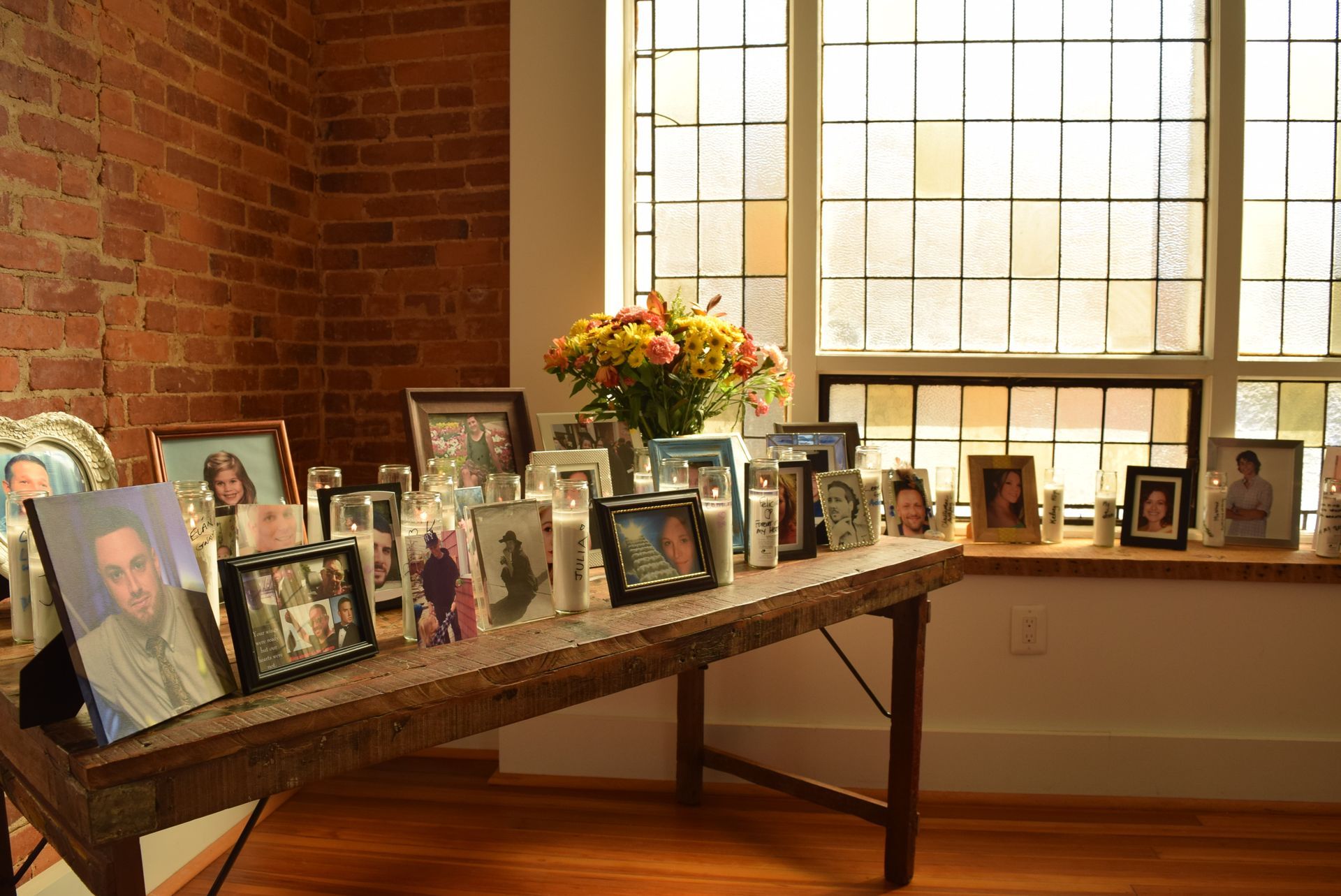 A table with a bunch of pictures on it in front of a window.