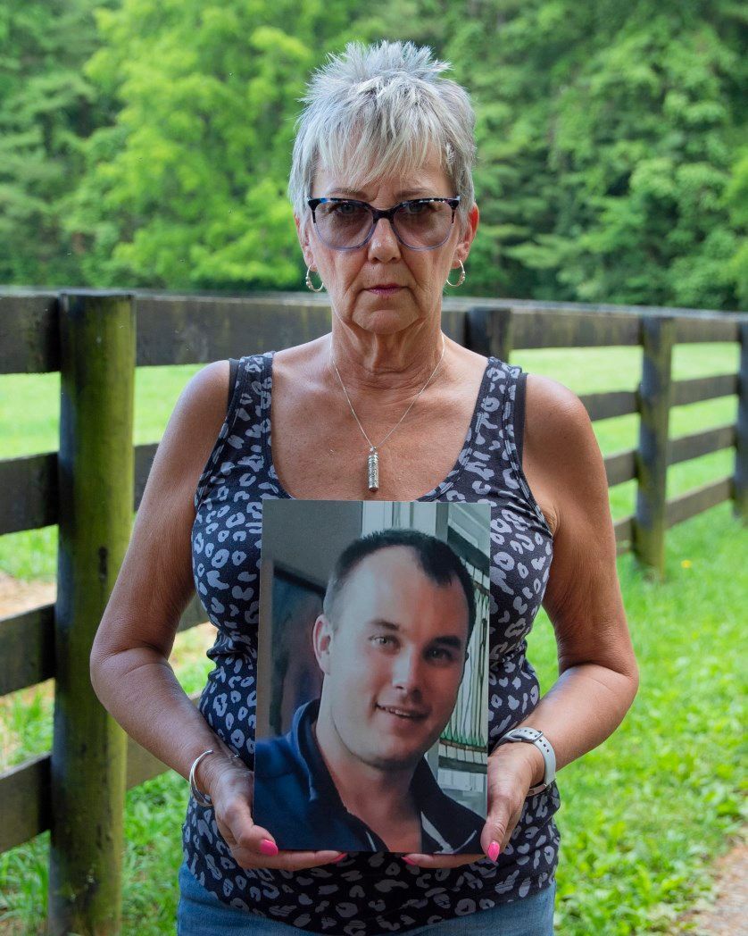 A woman is holding a picture of a man in her hands