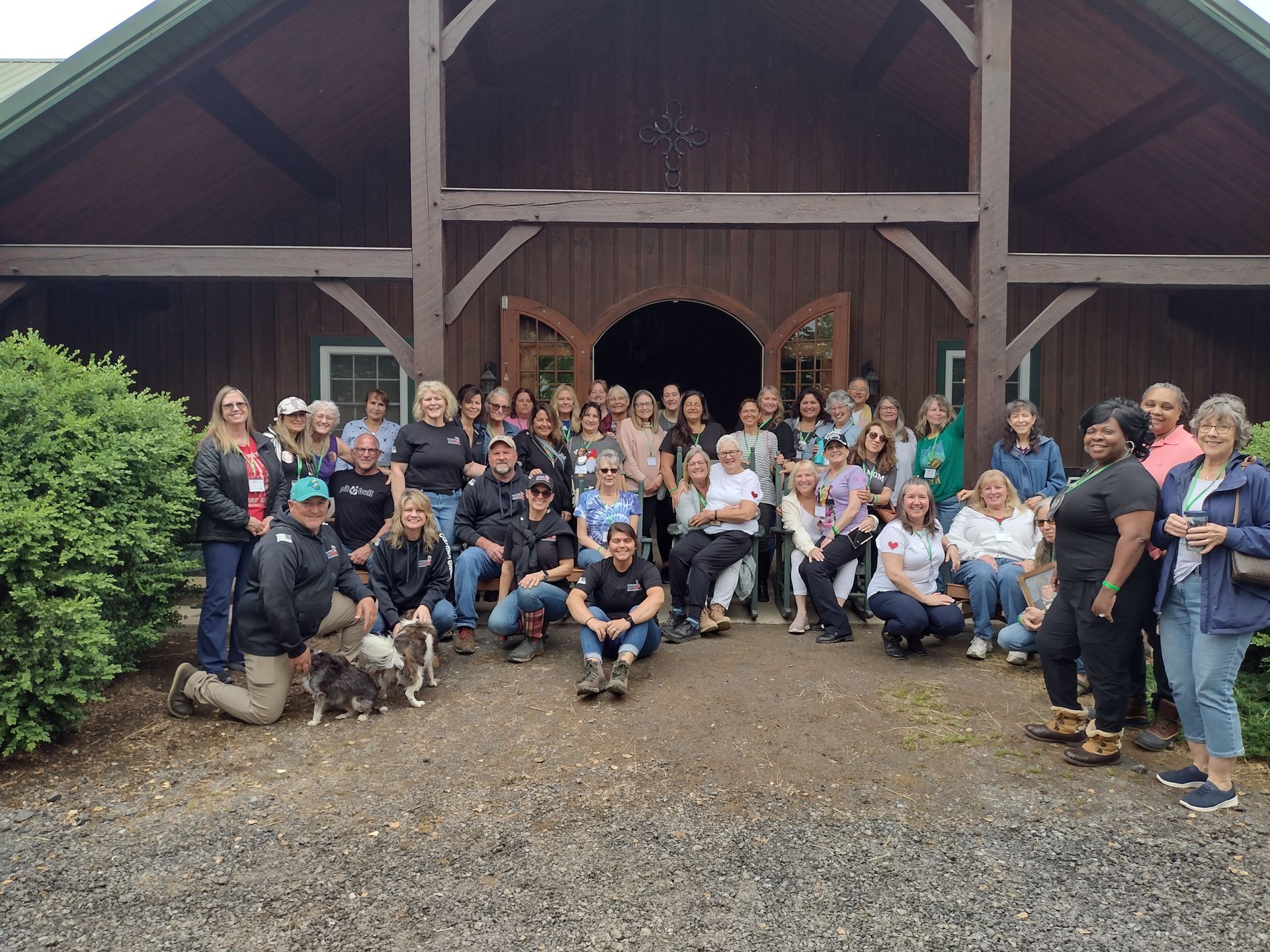 A large group of people are posing for a picture in front of a barn.