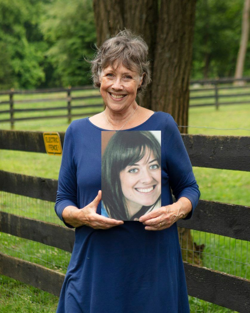 A woman in a blue dress is holding a picture of herself.
