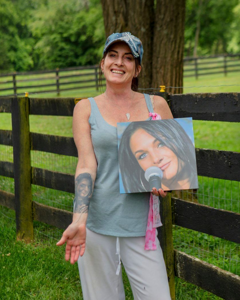 A woman is holding a painting of a woman with a microphone in her hand.