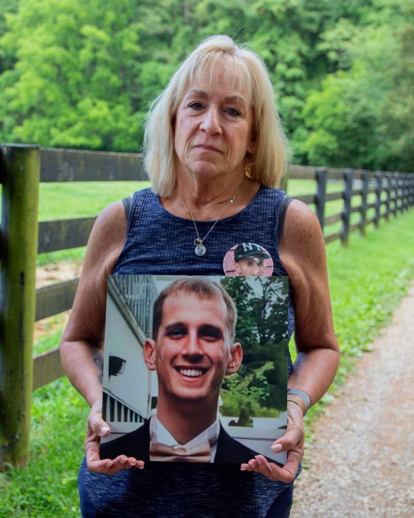 A woman is holding a picture of a man in a tuxedo