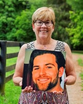 A woman is holding a picture of a man with a beard.