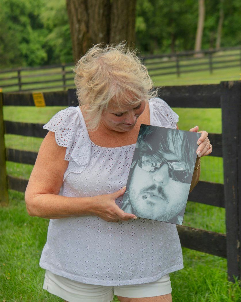 A woman is holding a picture of a man with a mustache