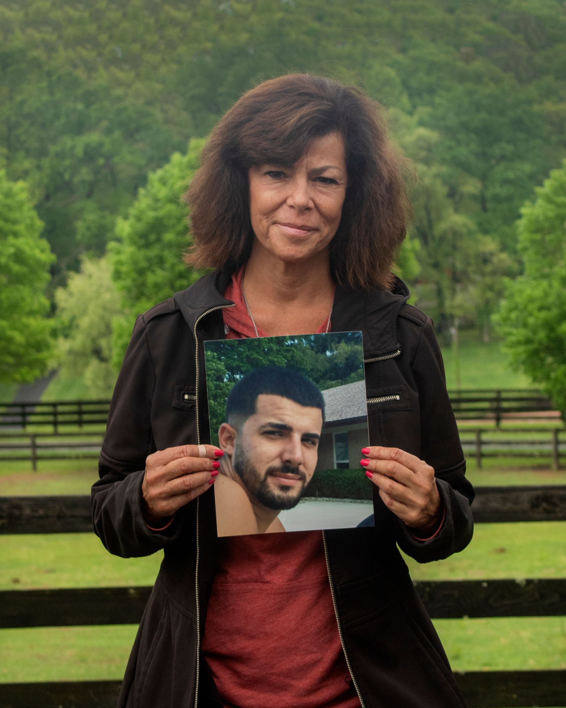 A woman is holding a picture of a man in a suit and tie