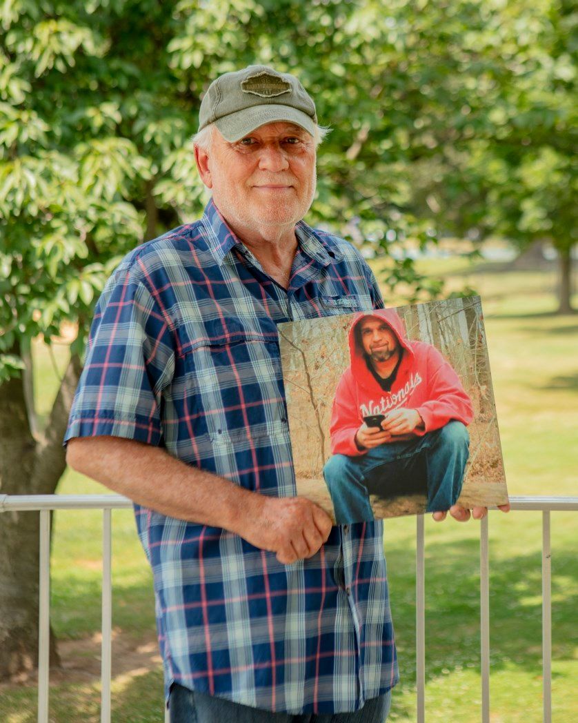 A man in a plaid shirt is holding a picture of jesus.