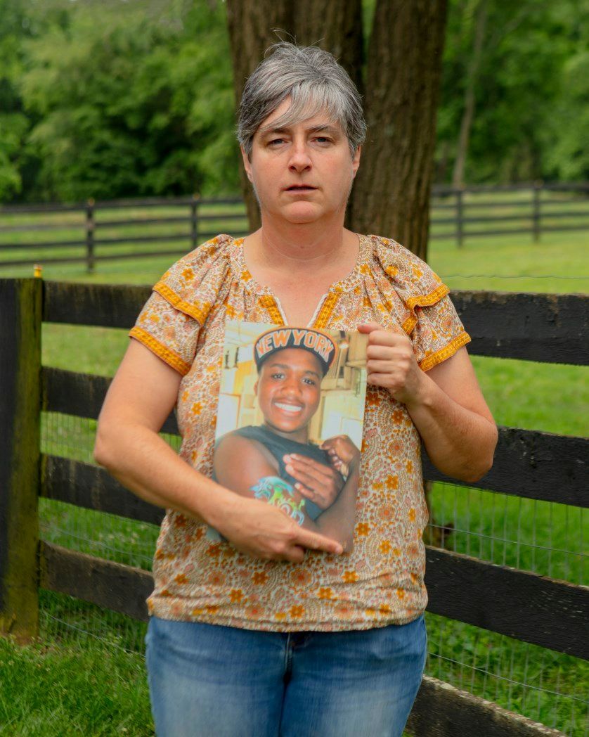 A woman is holding a picture of a man in a field.