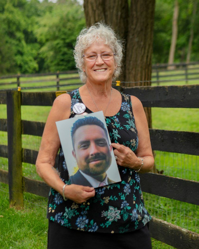A woman is holding a picture of a man in a suit and tie