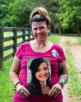 A woman in a pink shirt is holding a picture of a woman.