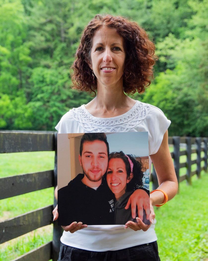 A woman is holding a picture of a man and woman