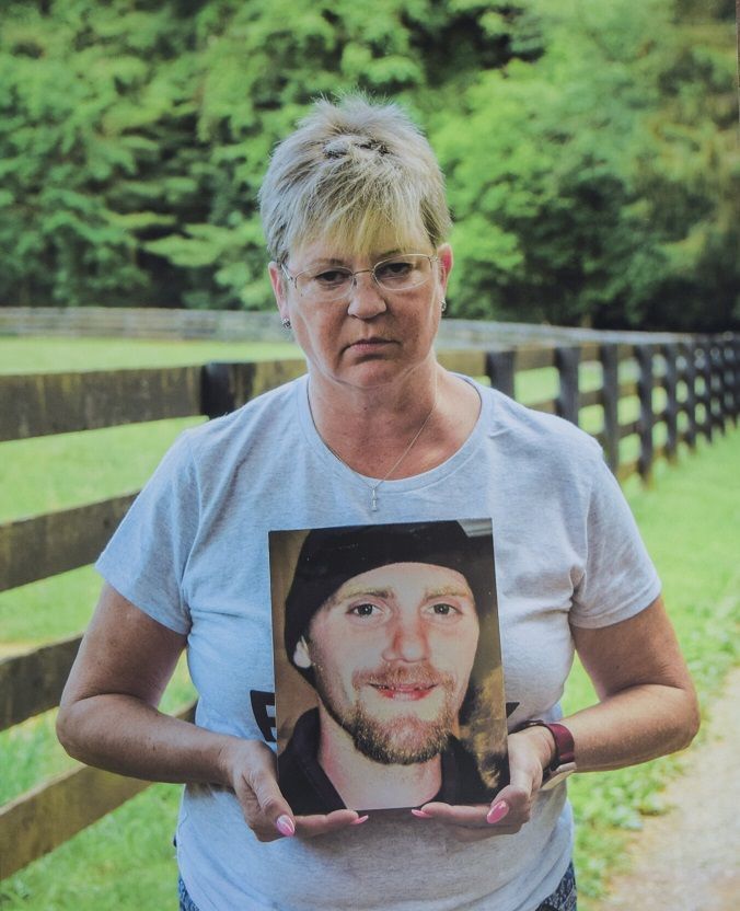 A woman is holding a picture of a man in a hat