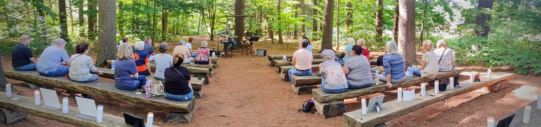 A group of people are sitting on benches in the woods.