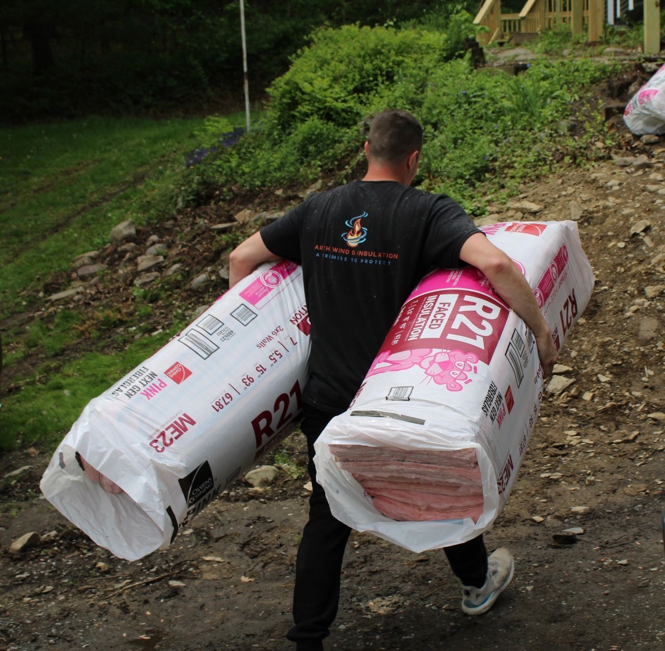 A man is carrying two rolls of r27 insulation
