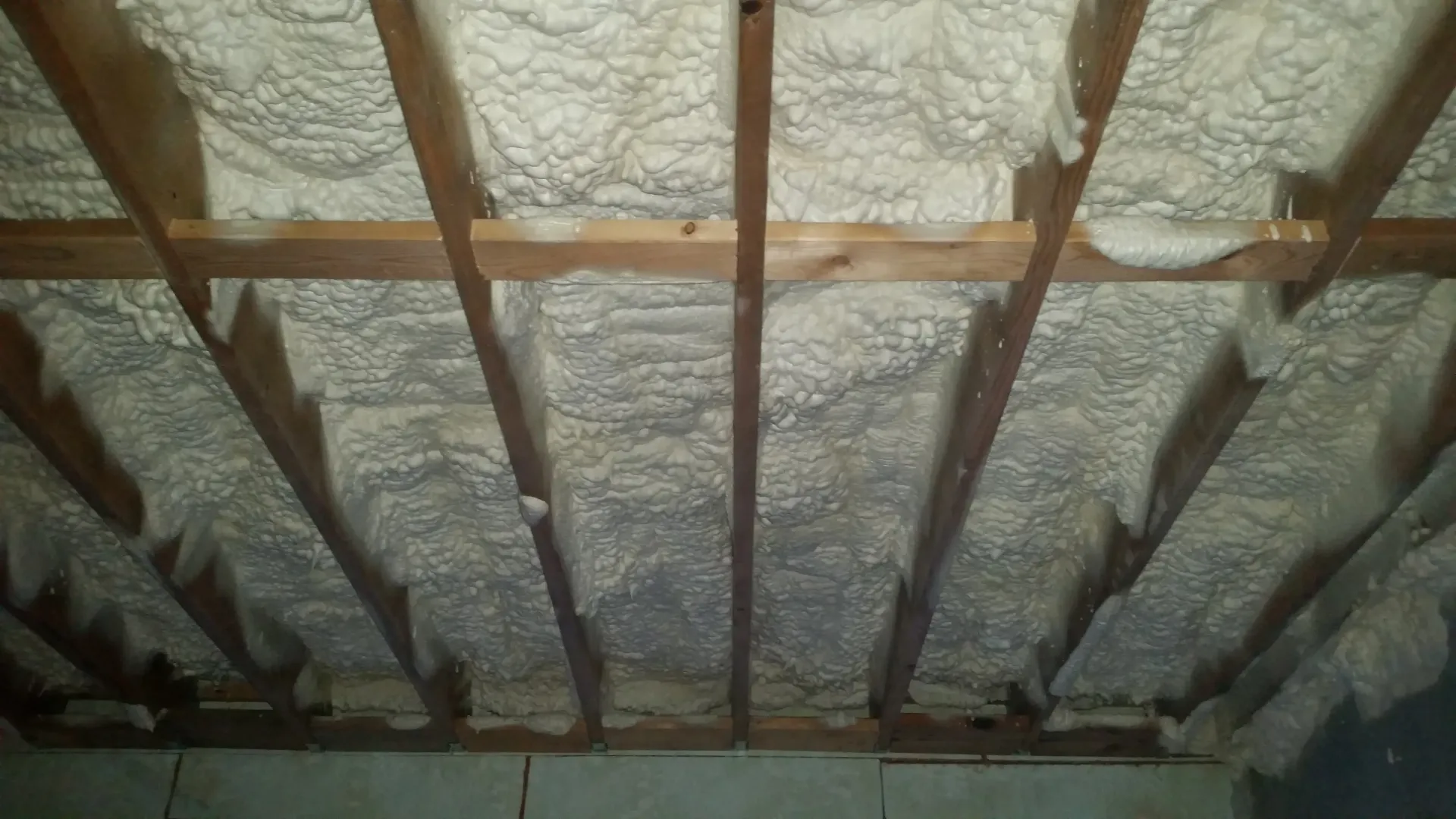 A basement with a lot of insulation and wooden beams.