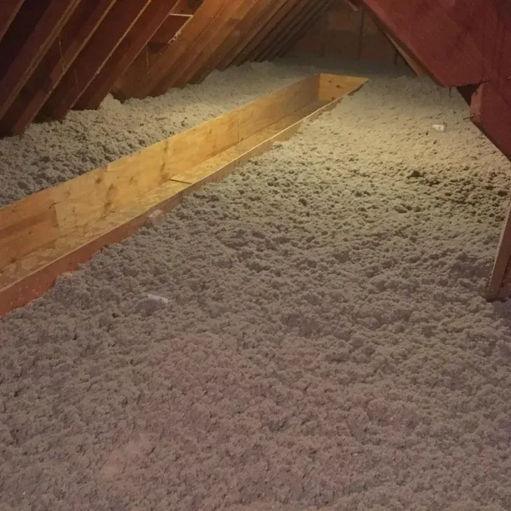 An attic filled with insulation and wooden beams.