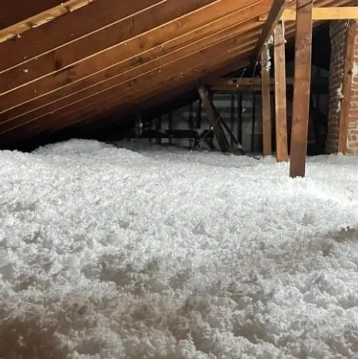 There is a lot of white insulation in the attic of a house.