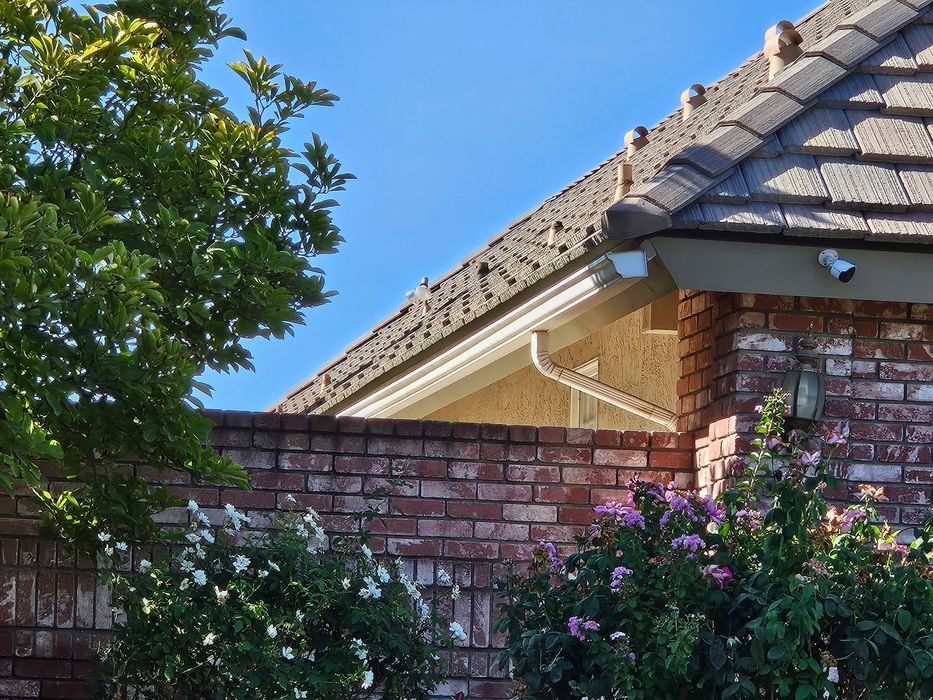 A brick house with a roof that has shingles on it