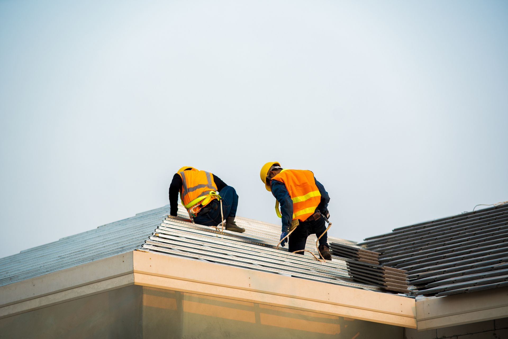Engineers in safety gear performing a residential roofing inspection on a modern home.