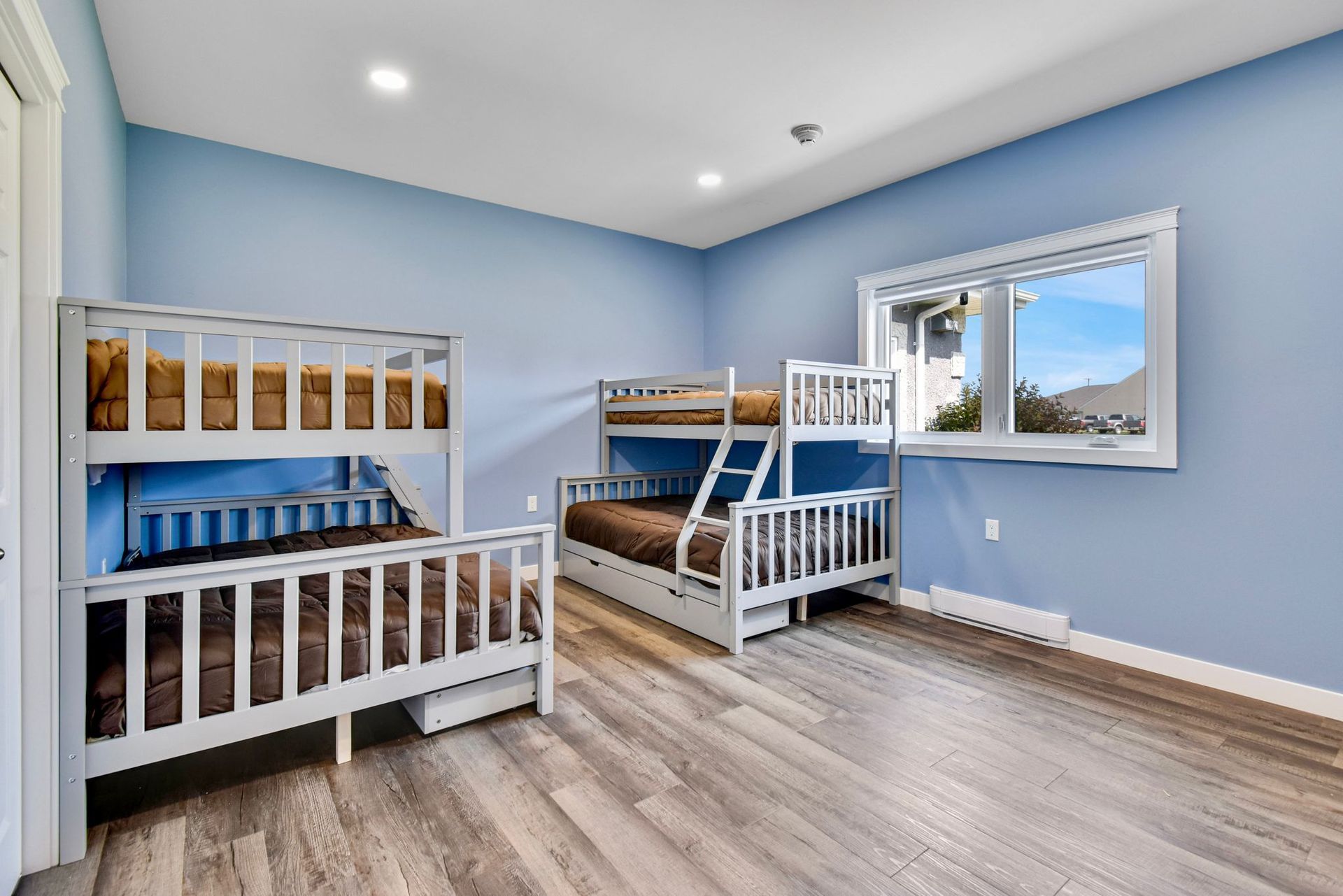A bedroom with three bunk beds and two windows.