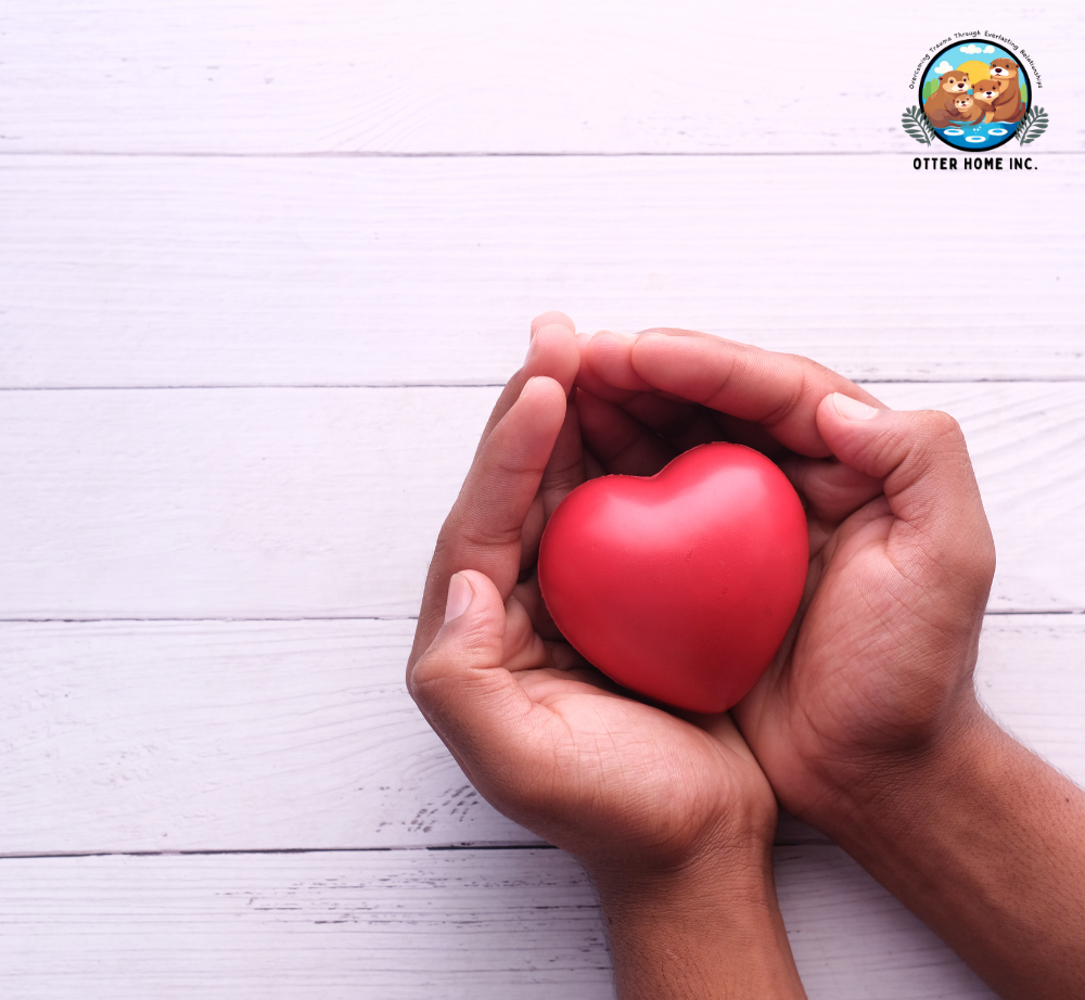 A person is holding a red heart in their hands