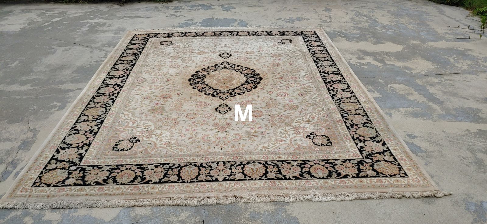 A large rug is sitting on a concrete floor.