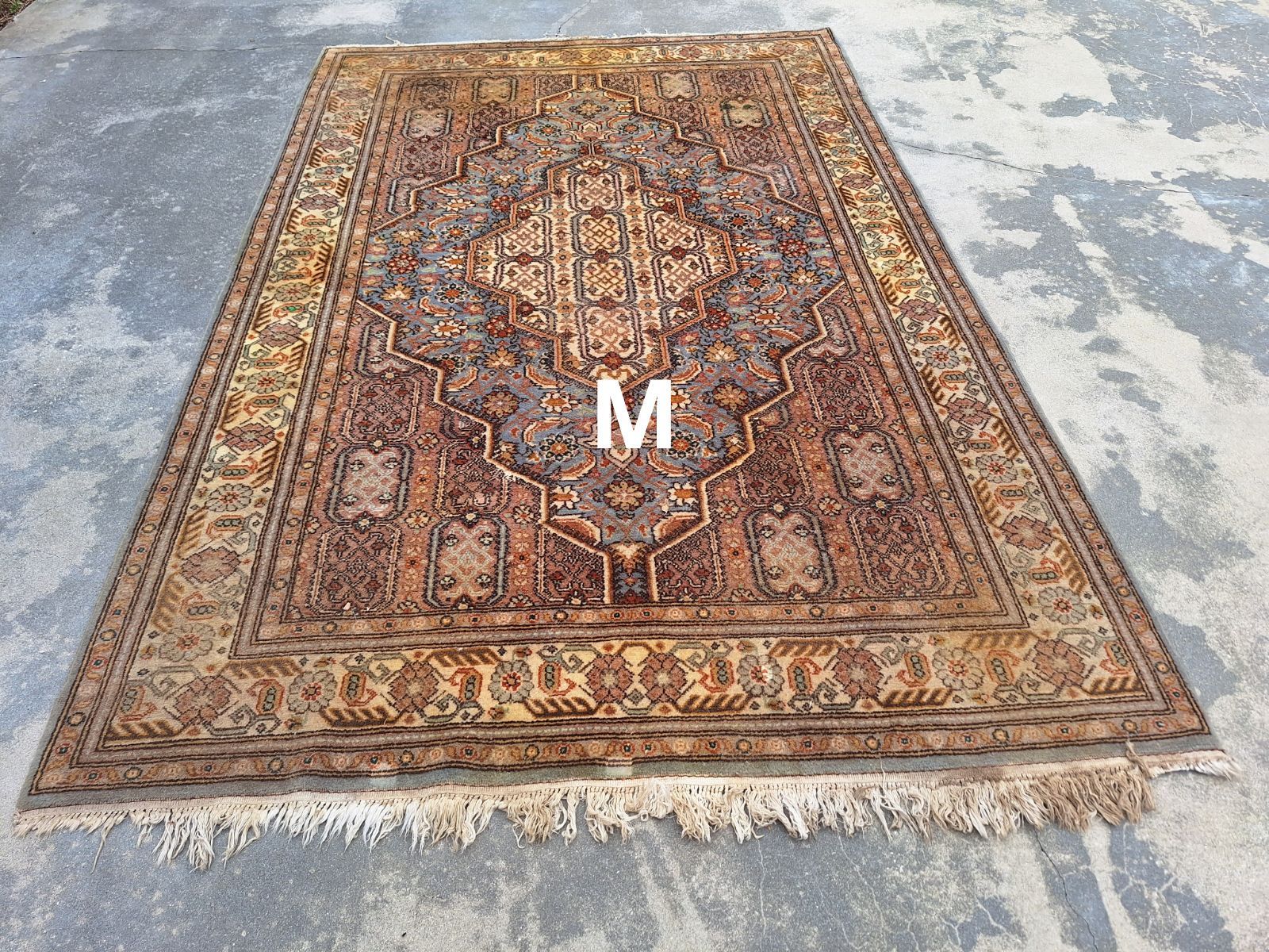 A large rug is sitting on a concrete floor.