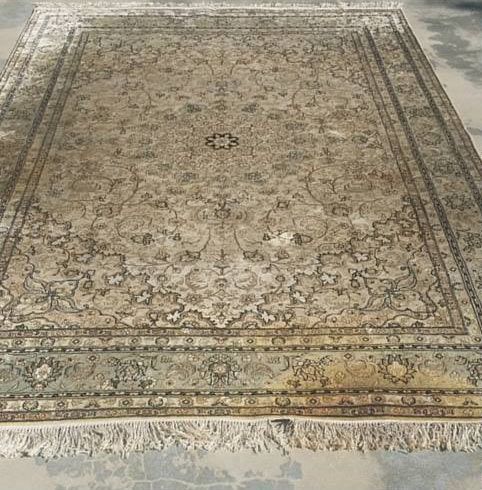 A large rug is sitting on a concrete floor.