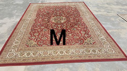 A red and gold rug with the letter m on it.